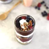 Vaso de yogur con fruta roja, arándanos y granola, una opción para después de entrenar