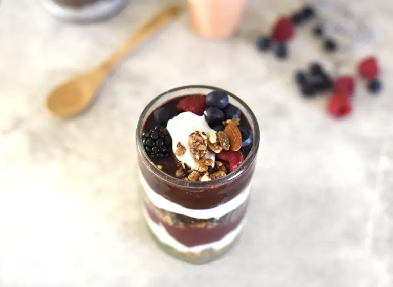 Vaso de yogur con fruta roja, arándanos y granola, una opción para después de entrenar